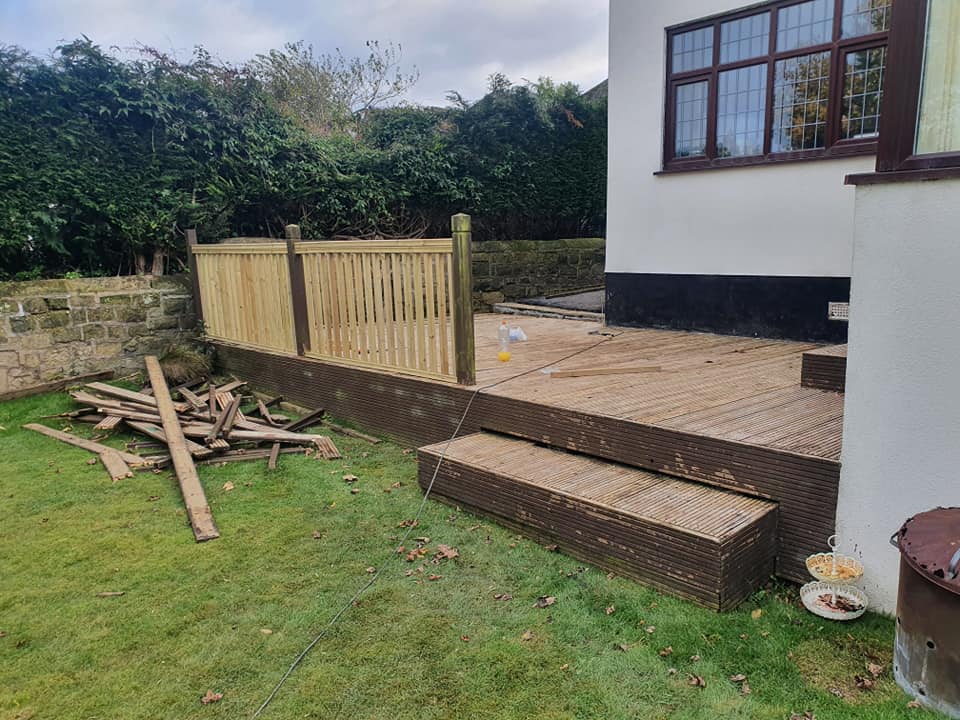 Composite decking with timber balustrade and steps, surrounded by construction materials in a garden setting, illustrating CK Fencing Contractors' decking solutions.