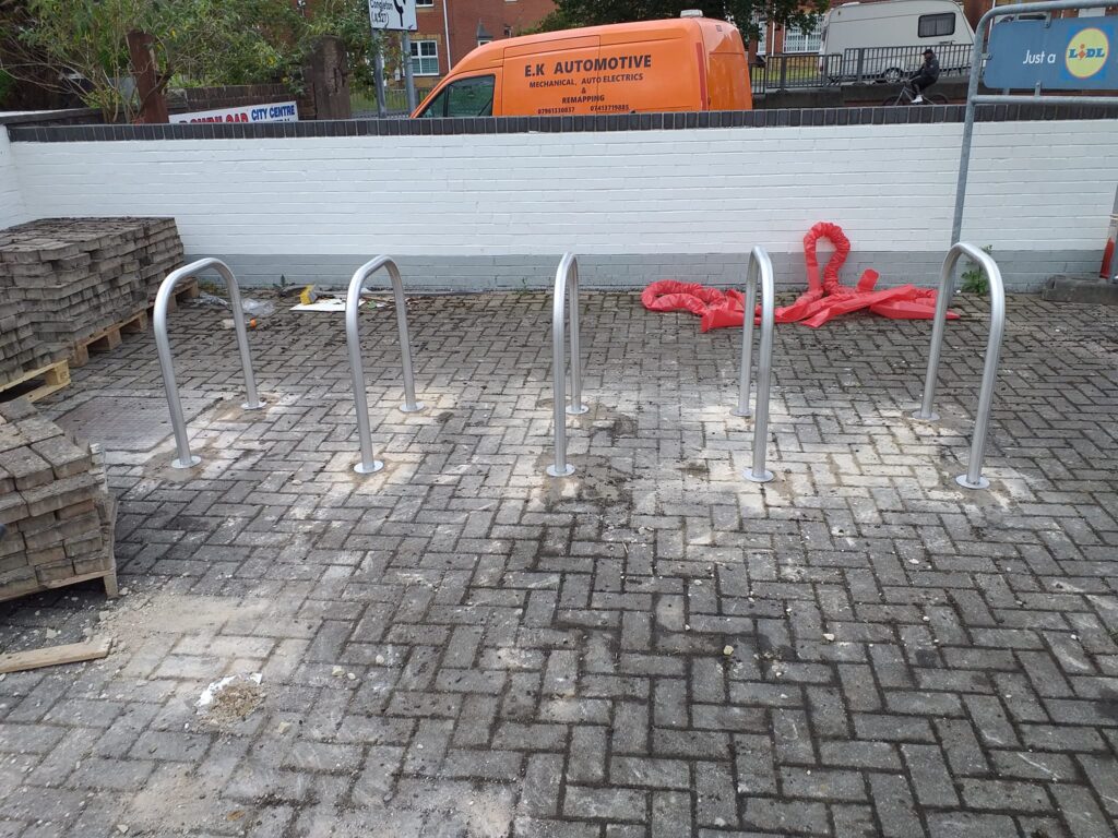 Bicycle parking stands installed on a paved area, part of a street furniture project by CK Fencing Contractors, enhancing urban infrastructure and safety.