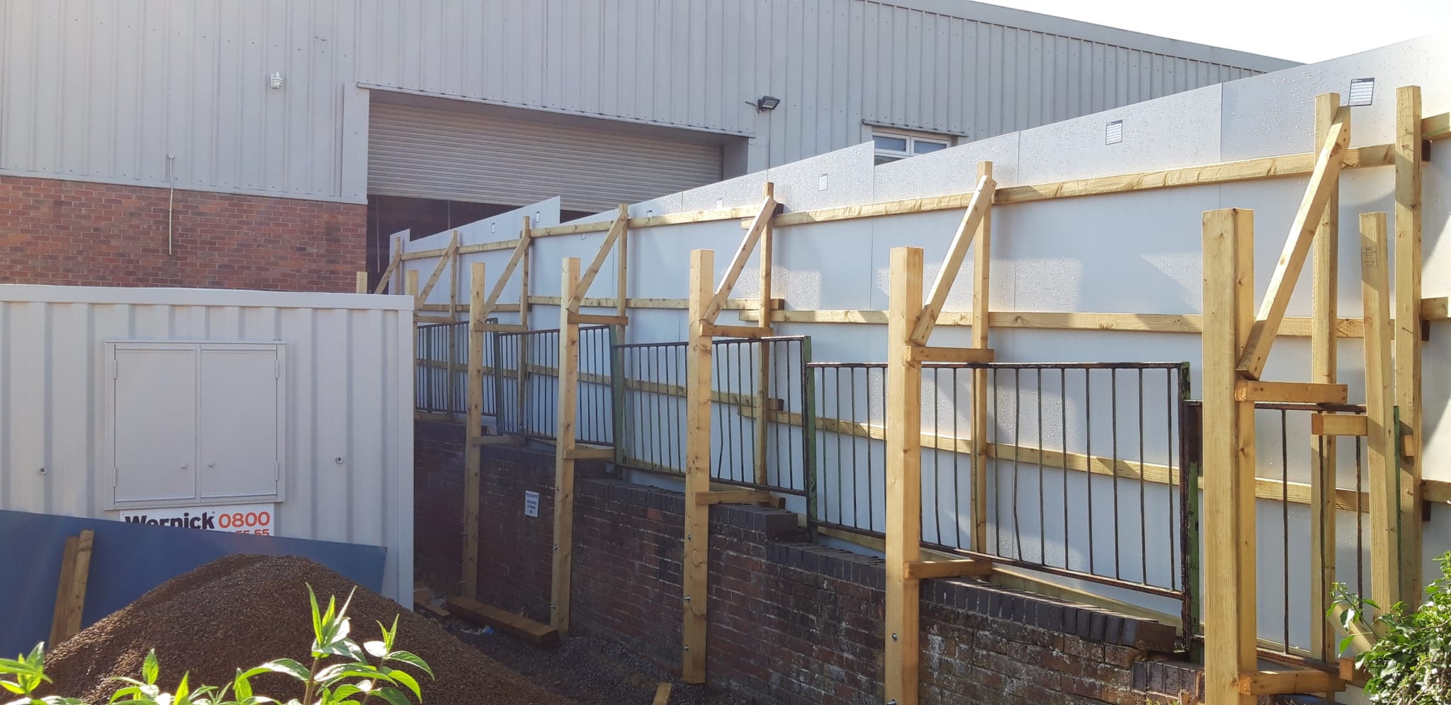 Temporary construction site hoarding system with wooden supports and anti-climb features, ensuring safety and privacy during site operations.