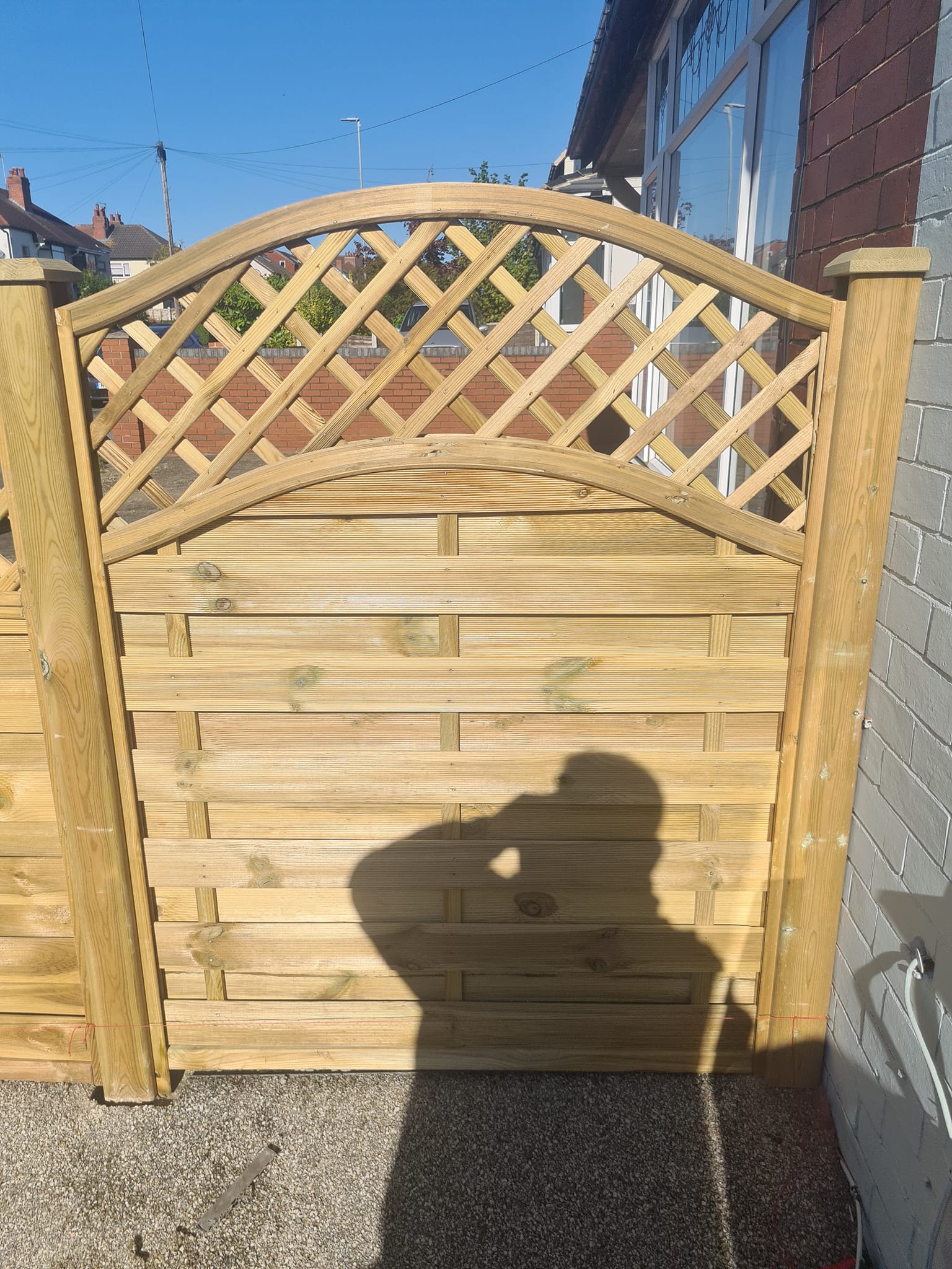 Wooden garden gate with lattice top, showcasing stylish design and security features, set in a residential area, emphasizing CK Fencing Contractors' bespoke offerings for driveway and pedestrian gates.