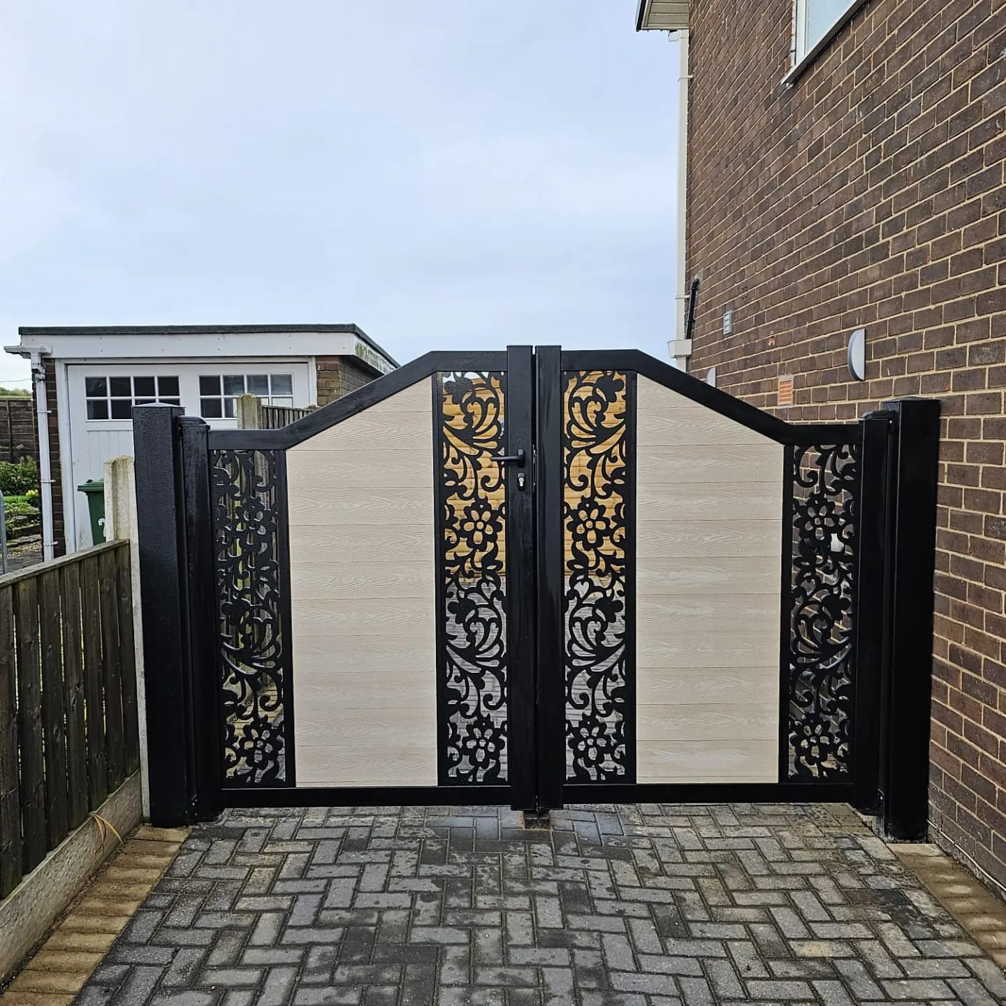 Stylish driveway gate with decorative metalwork and wooden panels, showcasing CK Fencing Contractors' garden and security fencing solutions in Castleford.