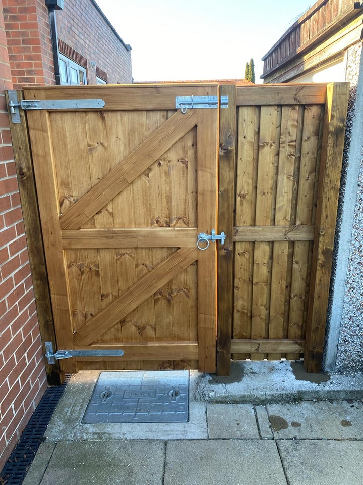 Bespoke wooden pedestrian gate with diagonal bracing and secure latch, installed in a residential setting, highlighting CK Fencing Contractors' quality craftsmanship.
