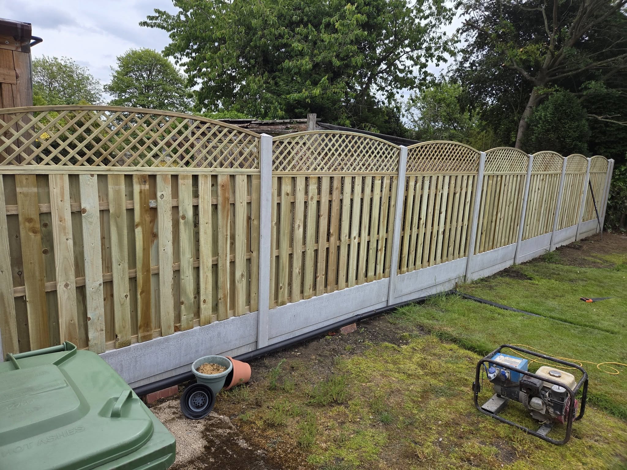 Garden fencing installation with wooden panels and decorative trellis, showcasing a neat outdoor space in Featherstone, emphasizing security and aesthetics.