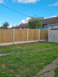 Residential garden featuring new wooden fencing, lush green lawn, and adjacent shed, showcasing outdoor improvements for security and aesthetics.
