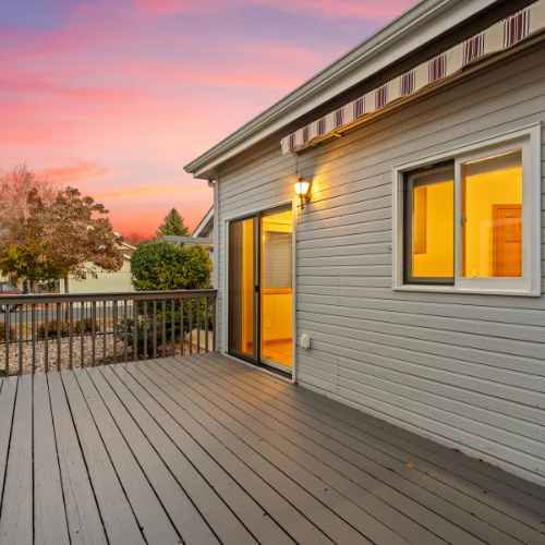 Modern composite decking with a sleek finish, outdoor lighting, and a sunset backdrop, showcasing a transformed outdoor space ideal for residential properties.